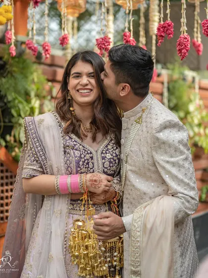 A sweet kiss on the cheek during an intimate Delhi wedding. This photo captures a tender moment between the couple amidst the celebration, showcasing their affection and happiness.