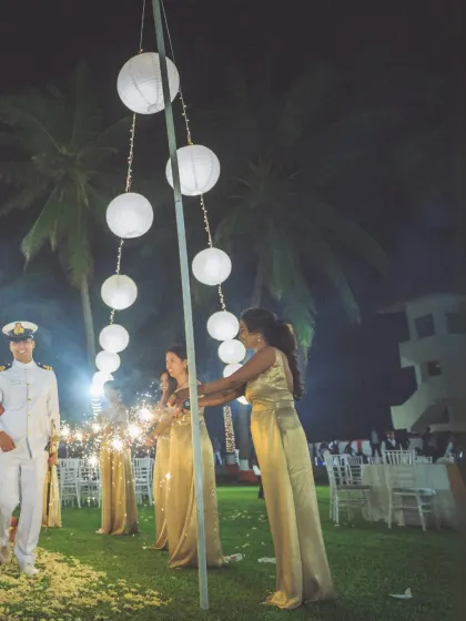 Bridesmaids in elegant gold dresses light the way with sparklers for the couple's entrance. This shot captures the warmth and support of friends on the wedding day.