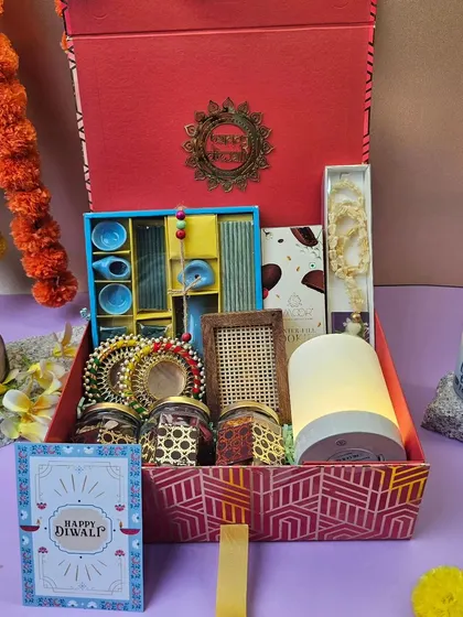 This grand Diwali hamper is designed to impress. It features a touch-sensor lamp, a set of ceramic cups, dry fruit jars, a scented candle, a pearl necklace, and a Diwali greeting card.