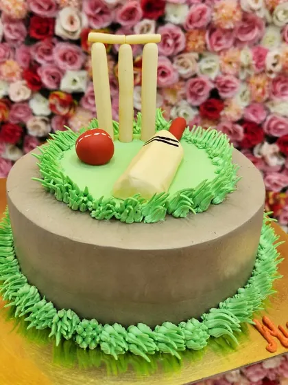 A cricket-themed cake with a fondant bat, ball, and wickets on a pitch. It's a classic design for any cricket fan.