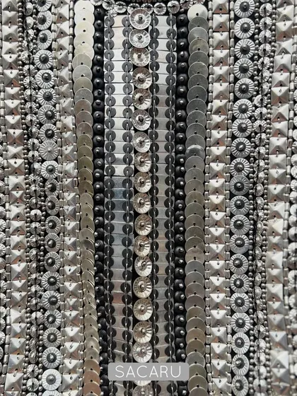 A detailed view of the meticulous hand embroidery on a brocade halter neck piece, showcasing rows of silver metal sequins and beads that create a stunning, light-catching texture.