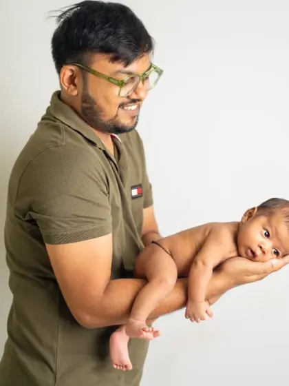 A father proudly holds his newborn in the palm of his hands. This classic pose beautifully illustrates just how tiny and precious a new baby is.