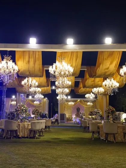 A wide view of the 'Golden Grandeur' reception, showing the magnificent canopy of drapes and chandeliers over the guest seating area, with the main stage visible in the background.