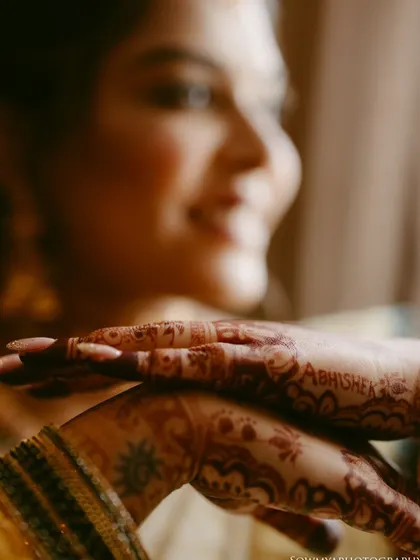 A soft-focus shot of a bride's hands, with the groom's name artfully hidden in her henna design.
