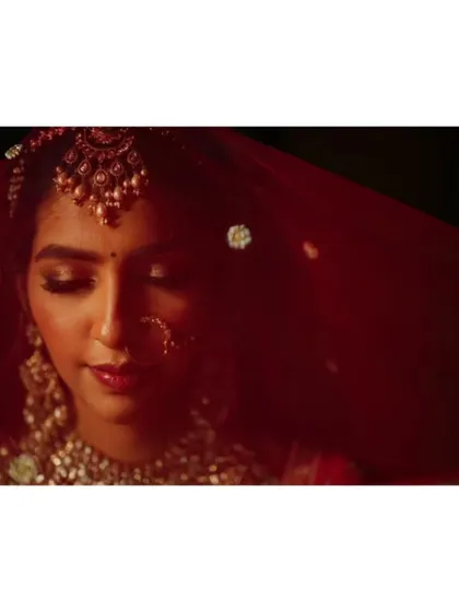 An artistic portrait of the bride under her red veil, with soft light highlighting her features.