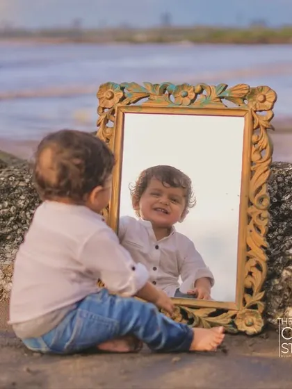 A toddler discovers his own reflection in a vintage mirror on the beach. A beautiful, introspective moment captured by the sea.