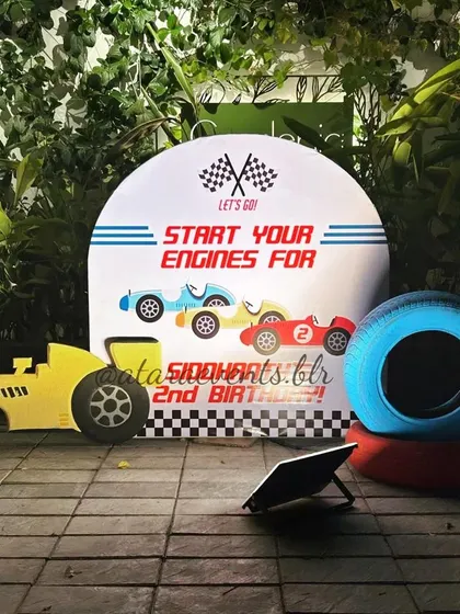 A simple yet effective photo op with a "Start Your Engines" sign, a race car cutout, and painted tires, perfect for capturing memories at the Mysore birthday bash.