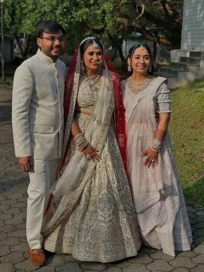 A precious family moment. The bride stands radiant in her ivory and red lehenga, her soft glam makeup looking flawless.