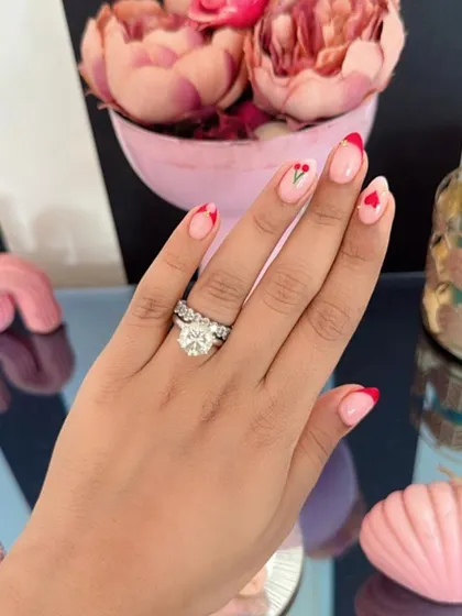 Nail inspiration showing a romantic set with red French tips, tiny hearts, and a tulip accent nail.