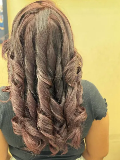 The back of a client's hair, showing off her new red hair color and the beautiful, cascading curls.