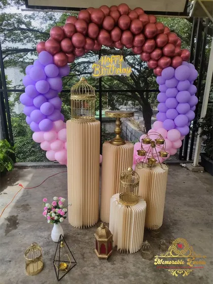 A beautiful outdoor birthday setup with a multi-colored balloon ring and elegant props.