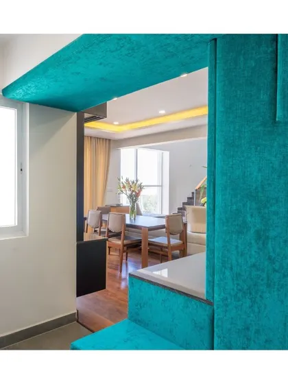 A tranquil view from a teal-accented entryway into a bright and airy dining room. The use of color and texture creates a calming transition between spaces.