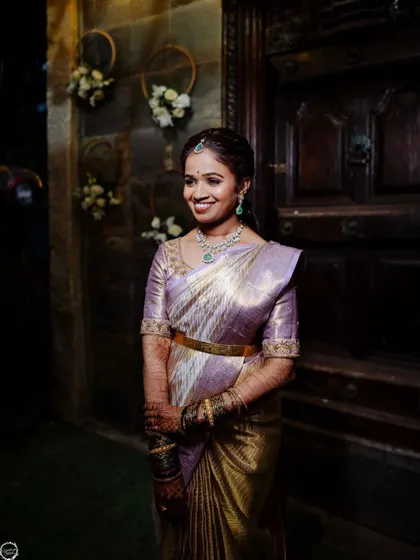 A happy and radiant client at her reception. The soft lighting highlights her glowing makeup and the beautiful sheen of her silk saree, capturing a moment of pure joy.