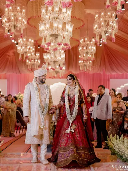 The couple walking down the aisle under a ceiling of magnificent chandeliers, a truly grand moment.