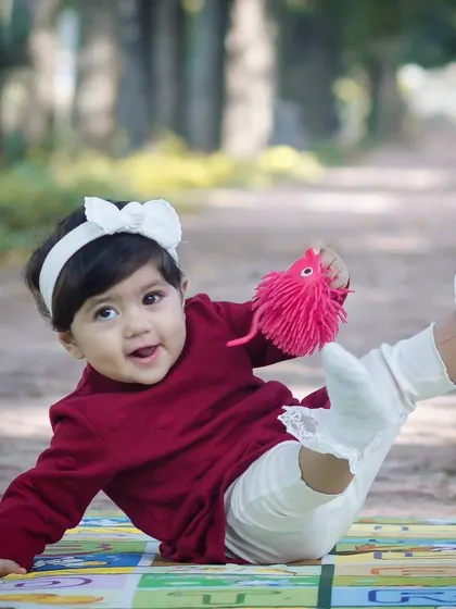 Play isn't just about fun; it's about experimenting and discovering the world. This photo captures a baby's joyful play on a mat during an outdoor kids photoshoot.