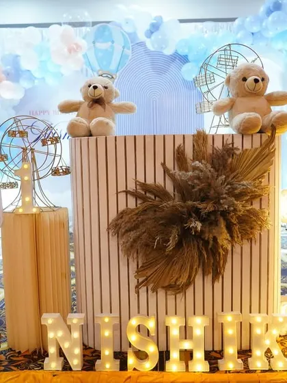 A lovely teddy bear theme in pastel blue, with a striped cake table and light-up name sign.