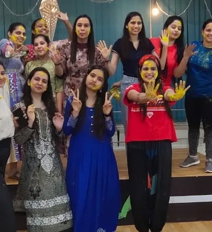The whole group posing after a fun-filled Holi dance session, with faces smeared with festive colors.