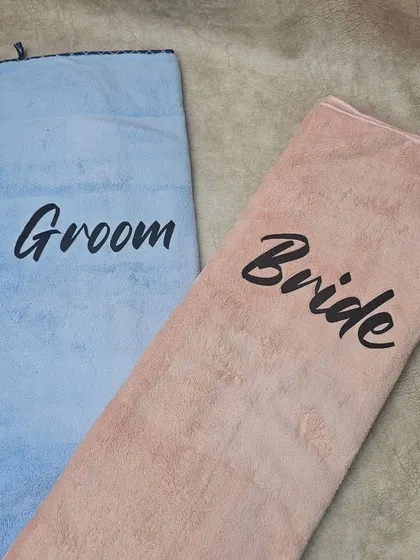 An unfolded view of the personalized 'Bride' and 'Groom' towels, showing their full size. They are made from a soft and absorbent material, making them both practical and special.