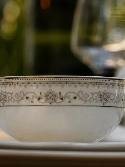 A detailed close-up of a bowl from a Vigneto dinner set. The soft, blurred background and focus on the intricate pattern highlight the craftsmanship and quality of the piece.