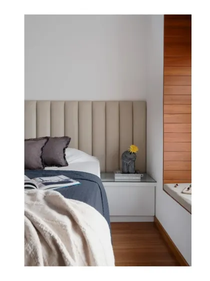 A close-up of the bedroom, showing the plush upholstered headboard next to the wood-paneled bay window seat.