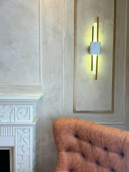 A cozy spot featuring a classic carved fireplace, a comfortable leather armchair, and a modern wall sconce. This image captures the beauty of mixing classic and contemporary elements to create a timeless and inviting corner.