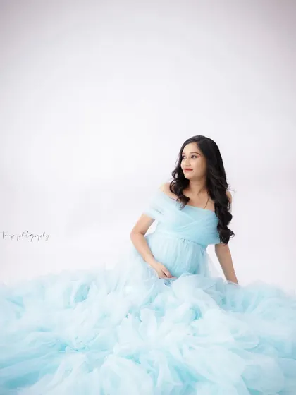 A duplicate of image 197, this serene portrait captures a mom-to-be seated in a cloud of light blue tulle, creating a dreamy atmosphere.