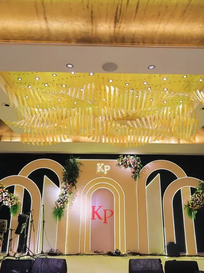 A grand stage for a cocktail night, with a custom monogram, modern arches, and a spectacular ceiling installation of golden ribbons.