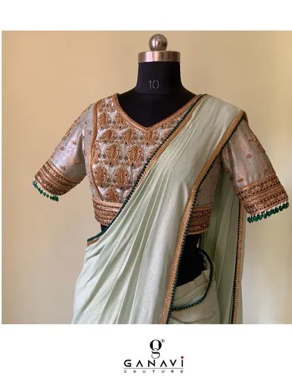 Celebrating fresh and dreamy hues, this fusion look combines a heavily embroidered blouse with a simple, elegant light green saree. The blouse features traditional motifs and brocade details.