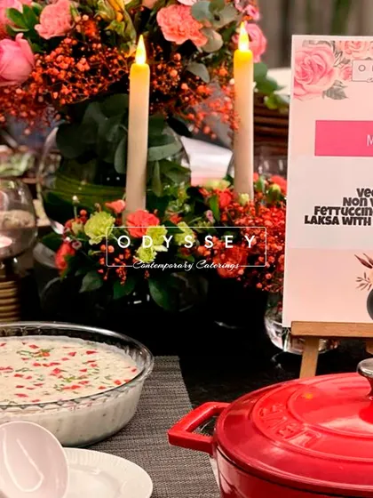A close-up of a menu for a CXO dinner, listing Veg Biryani, Non-Veg Biryani, and Fettuccine. The elegant floral arrangement and candles create a sophisticated dining atmosphere.