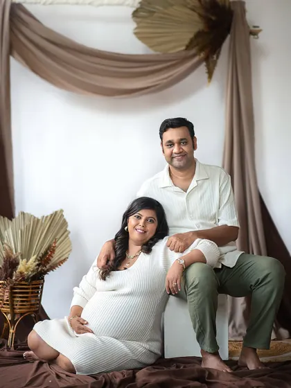 A warm and relaxed portrait from a boho-themed maternity session. The earthy tones and natural textures of the backdrop create a cozy and intimate atmosphere.