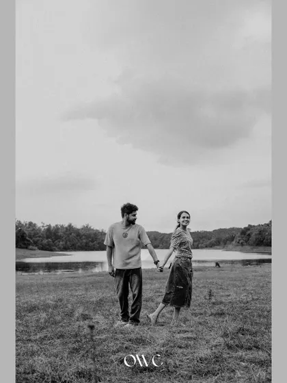 A wide-angle black and white shot of a couple by the lake, emphasizing the vastness and beauty of the natural landscape.
