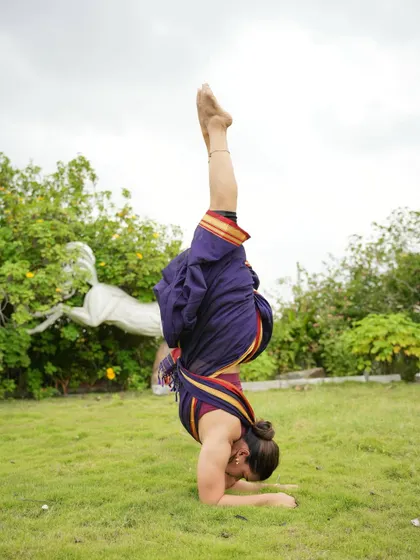 A straight Pincha Mayurasana (Forearm Stand) in a saree. This pose is a testament to the power of consistent practice, building the shoulder and core strength to hold a straight line upside down.
