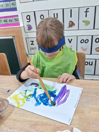 This child carefully moves the brush across the paper, creating a multi-colored abstract piece without seeing it. The final reveal is always a fun surprise.