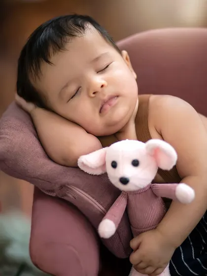 An intimate close-up capturing the peaceful expression of the sleeping baby, his soft cheek resting against the miniature sofa.