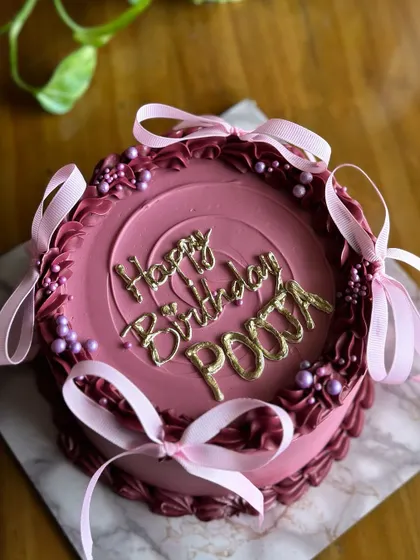 A slice of Victorian charm with a modern, minimal touch. This cake features a rich mauve color, delicate piping, and pretty pink ribbons for a simple yet elegant birthday.