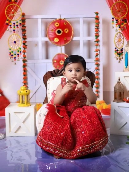 A thoughtful pose from a little girl in a gorgeous red lehenga during our Diwali mini-session. The entire set is decorated with lights and traditional hangings.