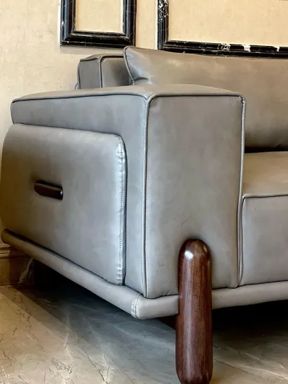 A close-up of the 'Academia Sofa's' arm, showing the dark walnut wood accent and the clean stitch detail on the vintage leatherette. These small details are what give the piece its sophisticated character.