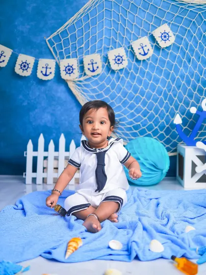 Ahoy, little sailor. This nautical-themed shoot is perfect for an adventurous little boy. The anchor banner, fishing net, and sailor suit create a classic maritime scene.