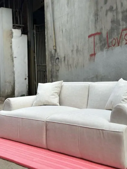 The full sofa shown against an industrial-style wall, demonstrating its versatility in different interior settings.