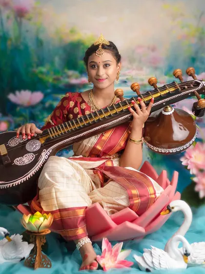 A stunning portrait of a young girl as Goddess Saraswati, holding the veena and surrounded by the beauty of a lotus pond.