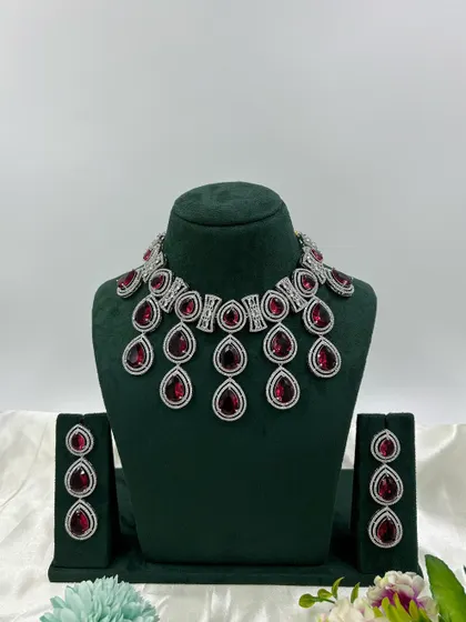 A modern necklace set with large, teardrop-shaped stones in a cascading design. This piece is available in several colors, including pink, green, and red, offering a bold and stylish look.