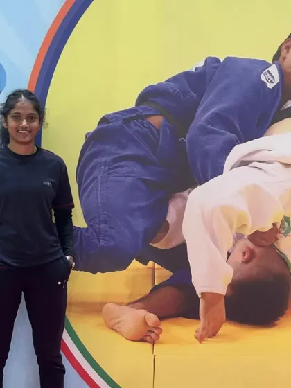 Our coach standing next to a poster of a Judo throw, embodying the art she teaches and excels in.