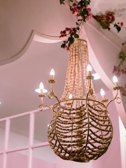 A detail from our ballroom-to-garden transformation. A beautiful beaded chandelier hangs in a custom-built pink archway, showcasing our attention to lighting and architectural details.