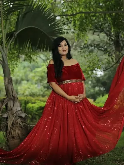 The sparkling fabric of this red sequin flying gown looks incredible in the sunlight. It's a glamorous choice for an outdoor maternity session.