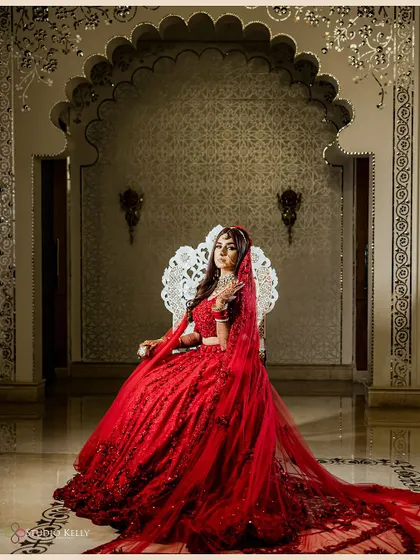 A regal bridal portrait of the bride seated on an ornate silver throne, looking every bit like a queen in her stunning red lehenga.