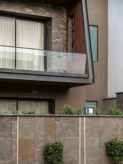 A daytime view of the Club Drive House boundary wall shows the subtle integration of the linear lighting strips. The design is clean and minimal during the day, transforming into a key feature of the landscape at night.