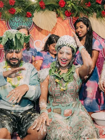 A candid moment of pure fun during a Haldi ceremony, where the couple gets playfully drenched by their friends and family.