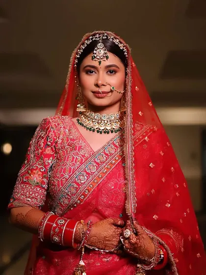 A full portrait of our stunning red bride. The entire look, from the dupatta setting to the makeup, is designed to be picture-perfect from every angle.