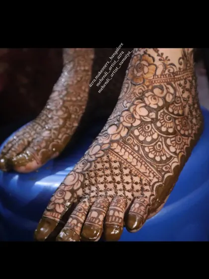 A close up of a bridal foot mehendi, showing the detailed floral and net pattern work.