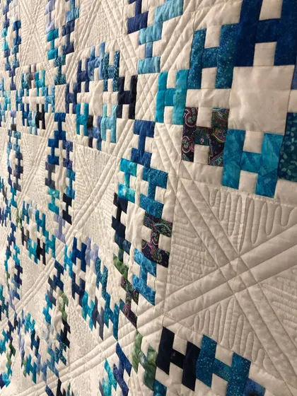 An angled close-up of the "Summer Wedding Ring" quilt, highlighting the texture from the quilting.